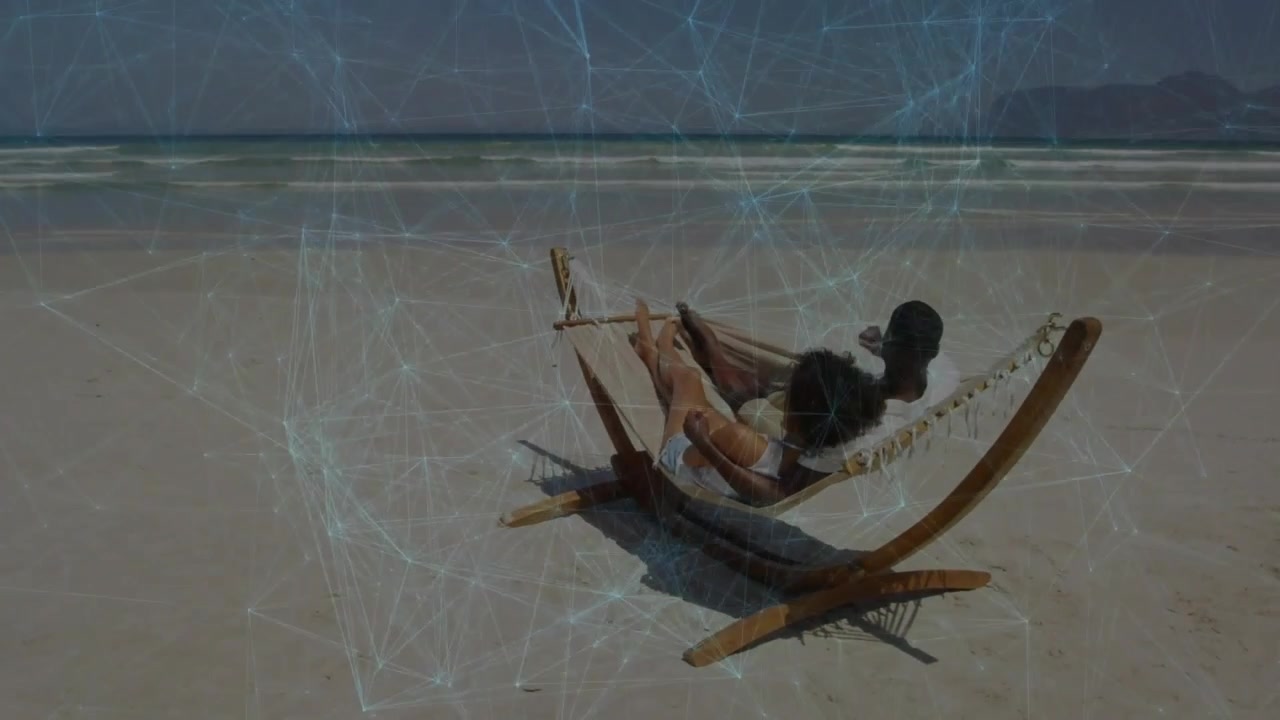 Woman lifting phone, man reclining in hammock on beach, wellness scene showing film-scratch overlay