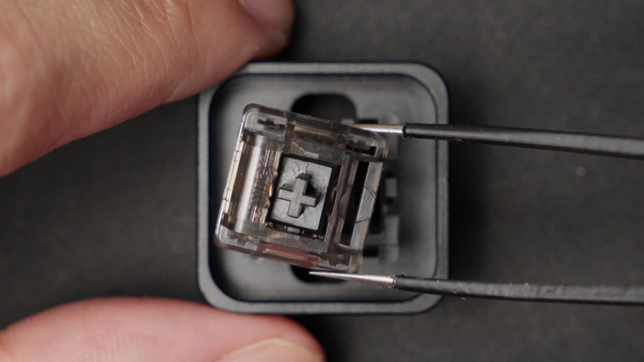 pinzas quitando componentes de interruptor de teclado roto, cerca de arriba hacia abajo tiro