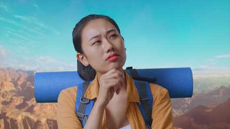 close up of asian female hiker with mountaineering backpack thinking about something and looking around while traveling at the top of mountain
