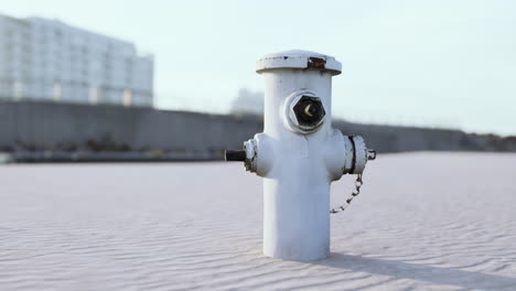 white fire hydrant on sandy ground near construction site