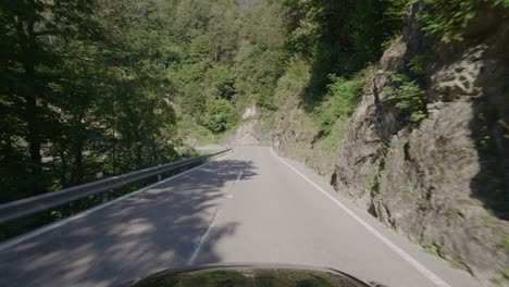 driving on a narrow mountain road in a forest in the italian alps