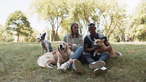 una pareja joven con mascotas, descansando en la hierba.