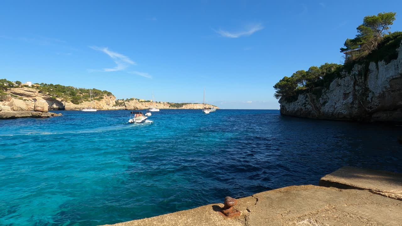 Lancha a motor se afastando da costa no mar azul em Maiorca, Espanha.