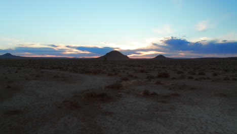 Fast,-low-altitude-flight-over-the-Mojave-Desert-basin-towards-dormant-cone-shaped-volcanos-towering-over-the-landscape