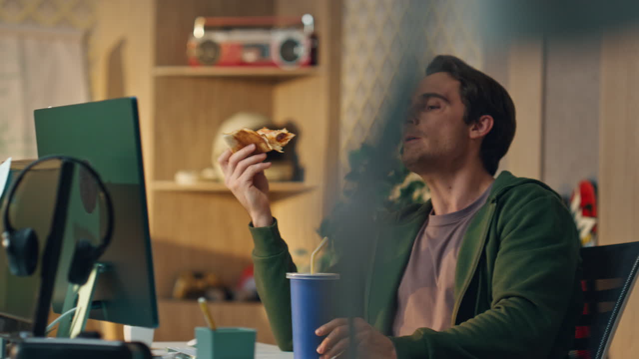 hombre hambriento bebiendo cola sosteniendo la oficina de pizza de cerca. descanso de almuerzo freelance