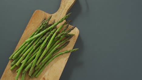 video of asparagus on wooden chopping board over grey background