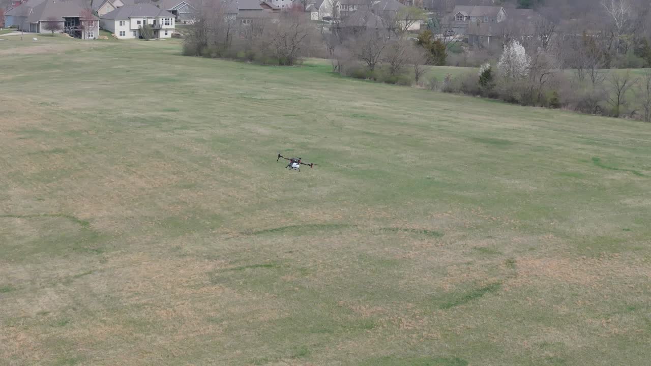 Ag spraying drone flies over a field, spreading chemicals over grasslands