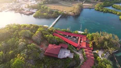 aerial top view of tropical island coast, sailboats and colorful reef , red roof houses in roatan island, atlantida, honduras