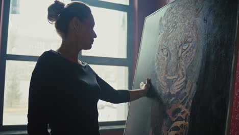 woman viewing a painting of a leopard in an art studio
