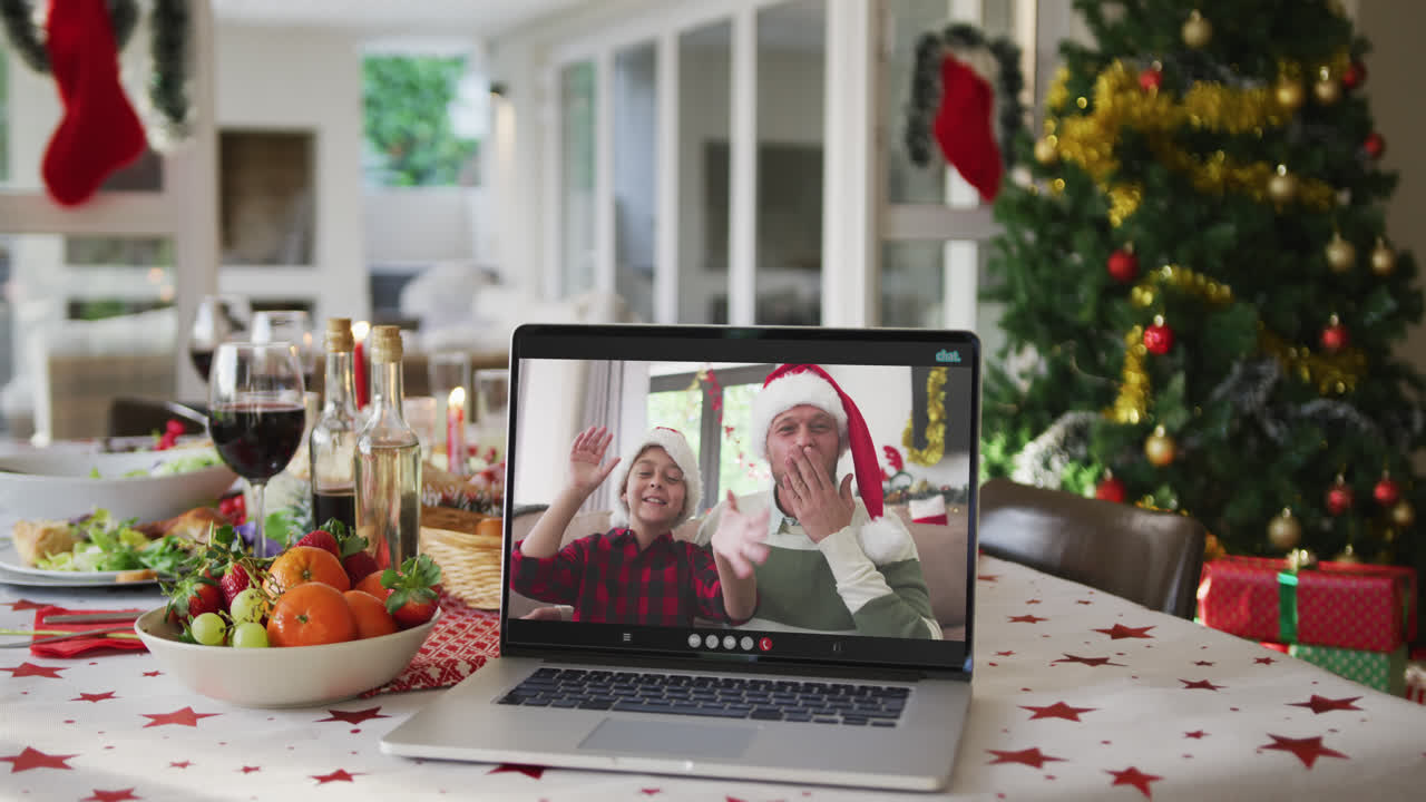 padre y hijo caucásicos felices en la computadora portátil acostados en la mesa de navidad