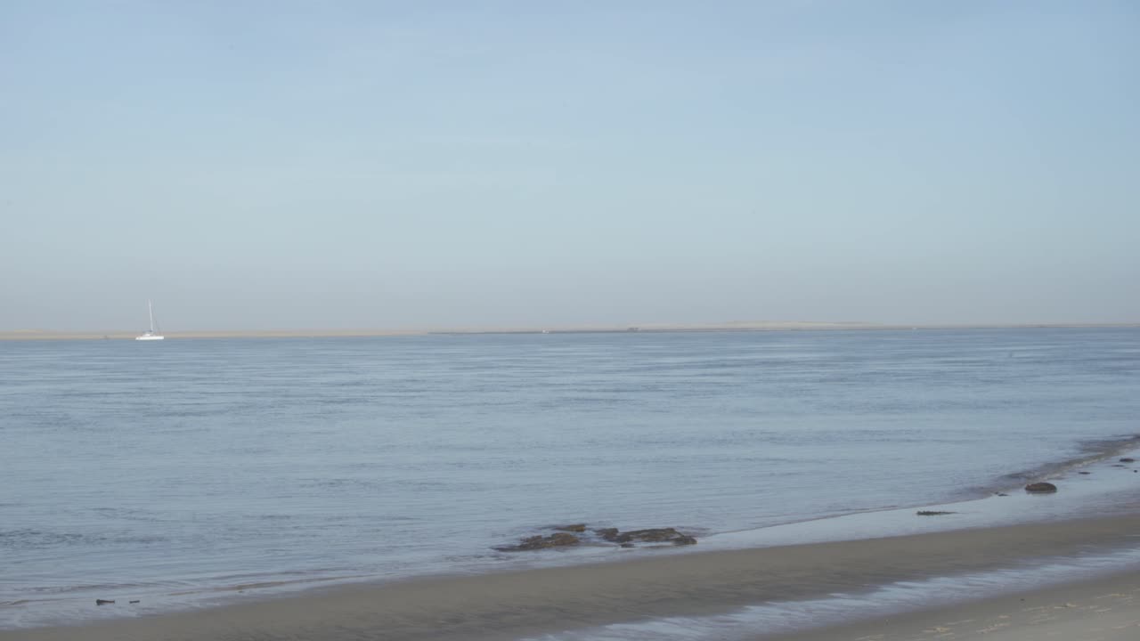 A white sailboat highlighted by the sunlight on the coast of Marseille, France - wide shot