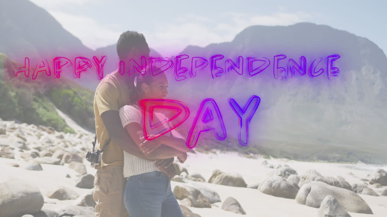 Animation of text independence day over african american couple embracing at beach