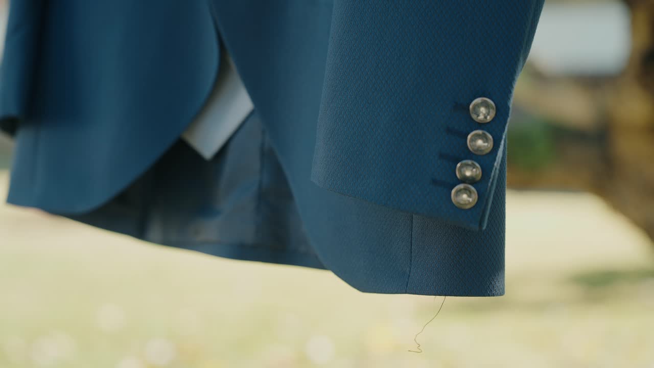 Dettaglio della manica di un elegante abito da sposo blu che mette in risalto la sartoria raffinata
