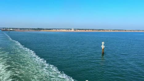 leaving land, heading to sea with white wake and blue sky