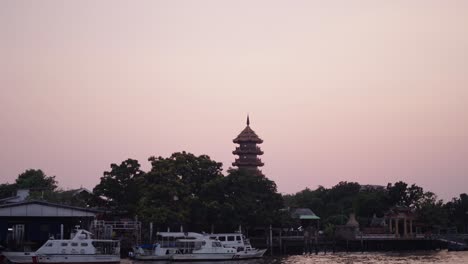 sunset over the chao phraya river with a pagoda in bangkok