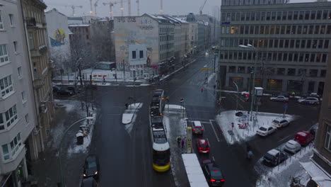 Forwards-tracking-of-tram-leaving-stand-and-passing-through-crossroads.-High-angle-view-of-streets-of-city-in-winter.-Berlin,-Germany