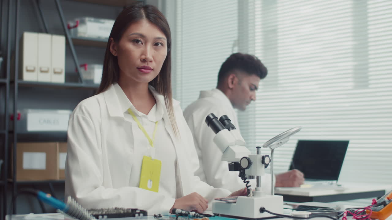 Female Engineer with Microscope Looking at Camera