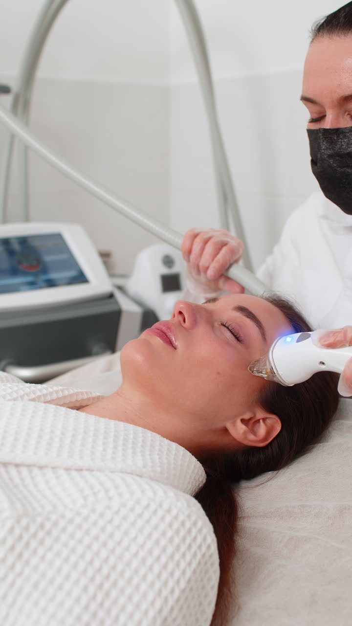 Woman gets rf lifting therapy under eyes with modern device in beauty cosmetology clinic session