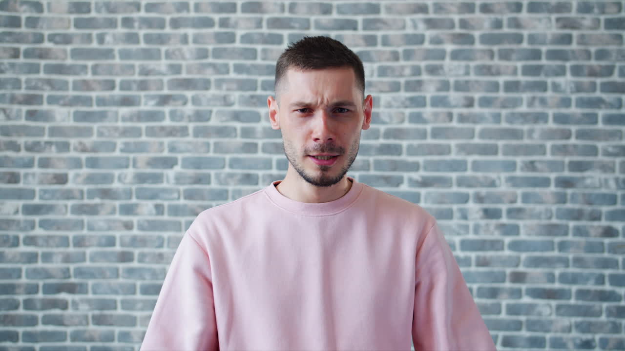 Man expressing anger in front of a brick wall