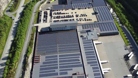 massive solar panel installation on asko industrial building in arna norway - upward moving aerial with highway passing on left side
