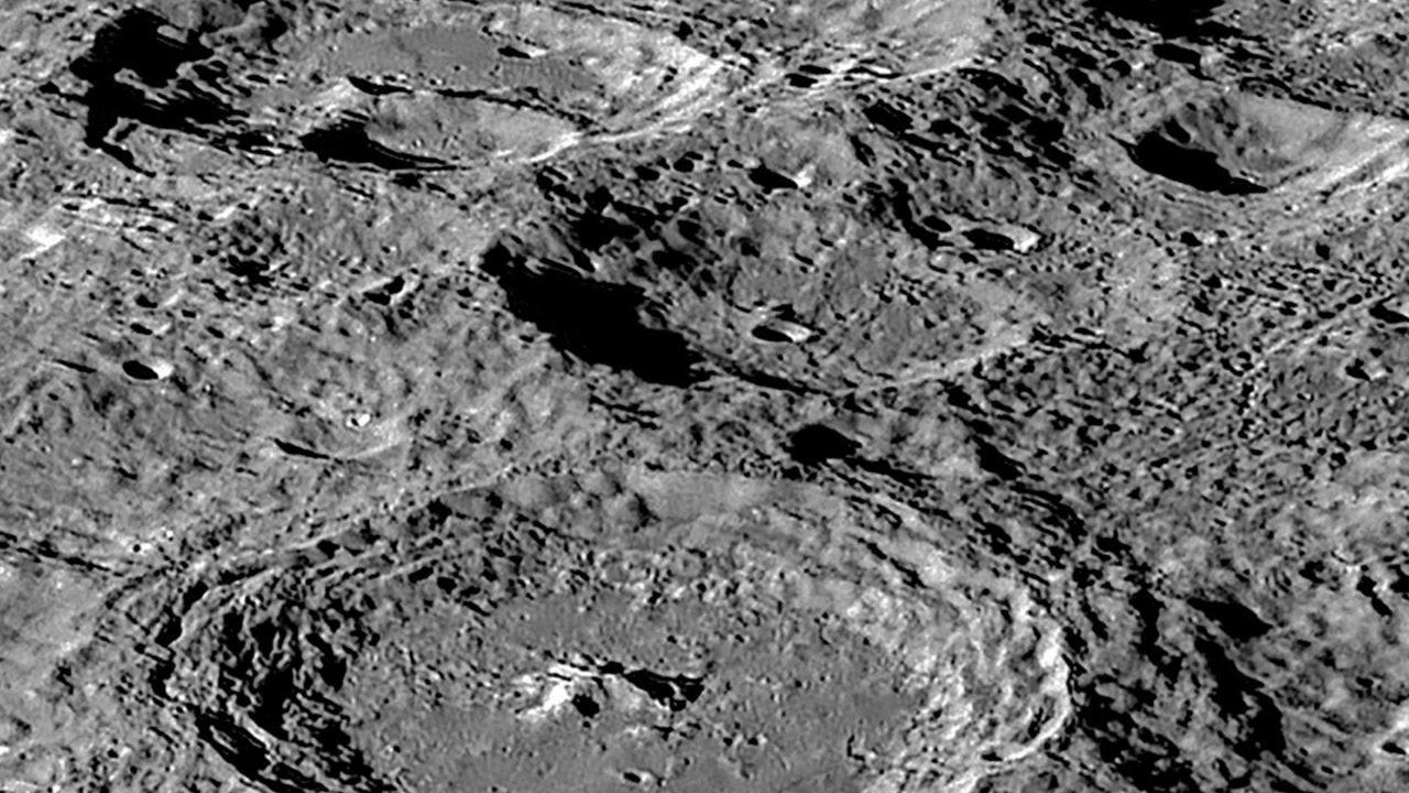 A close-up view of the rugged lunar surface showing multiple overlapping ancient impact craters and deep shadows.