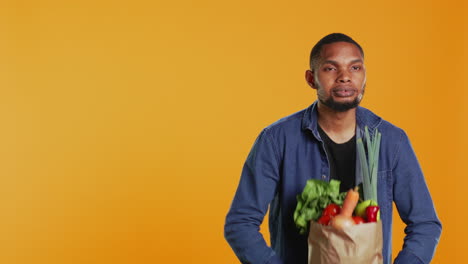 young adult pretending to lift weight with a paper bag full of bio groceries