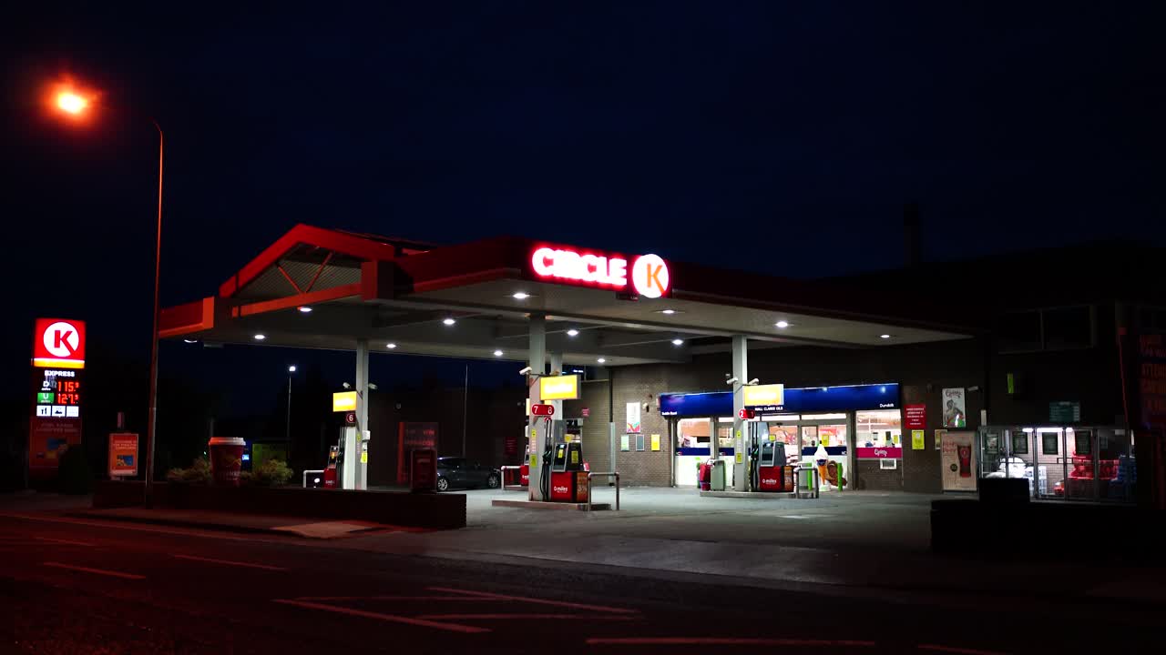 Illuminated signs at an empty gas station at night , view from the road at the gas station in Dundalk , Ireland