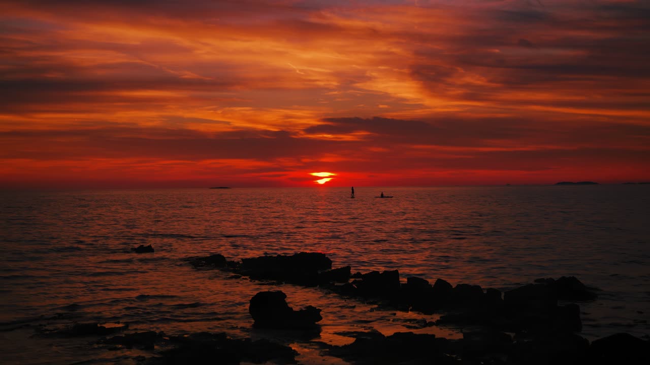 Sunset SUP experience in Istria Croatia with reflections of red sky on peaceful ocean water