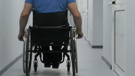 un hombre en silla de ruedas conduce por el pasillo. una persona con discapacidad se mueve por el hospital.