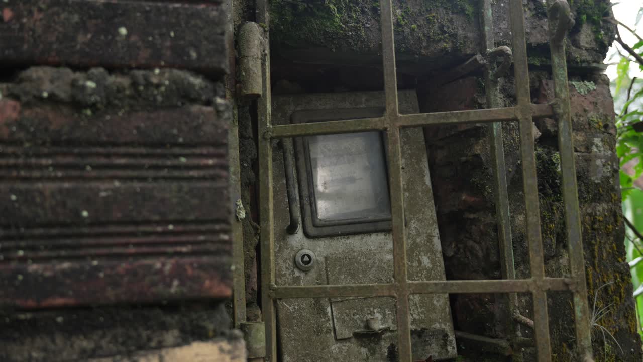 Old weather-beaten utility meter electricity or water enclosed within a protective metal cage