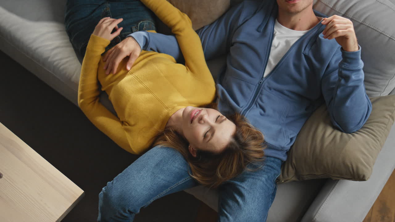 Romantic couple talking home top view. Happy relaxed wife lying husband knees