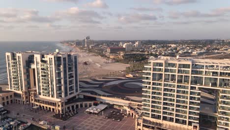 un vuelo entre puntos altos hasta el mar con la playa y turistas en la ciudad de herzelia en israel