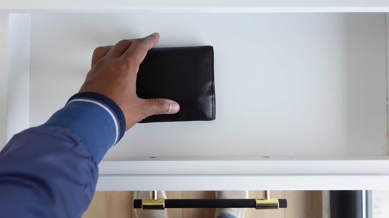 una persona abriendo un cajón con una billetera dentro