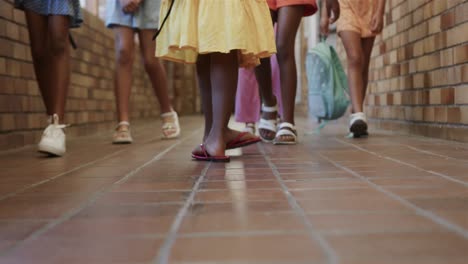 Diverse-schoolgirls-with-school-bags-walking-at-elementary-school-corridor-in-slow-motion