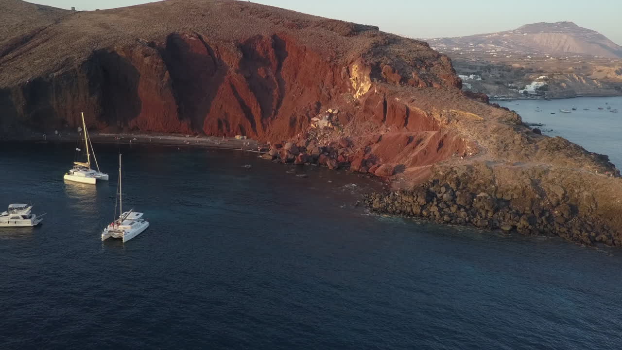 los barcos anclan en la famosa playa de los acantilados rojos de kokkini paralia en santorini.