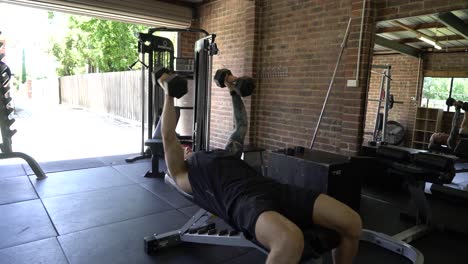 Tattooed-man-in-home-gym-chest-fly-dumbbells