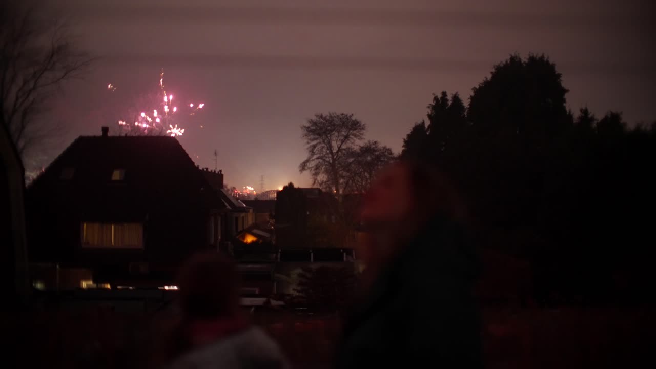 Silhuet af mor og barn, der ser fyrværkeri på nattehimlen under Nytår fejringen i Oosterbeek