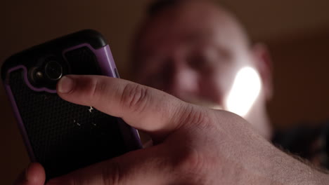 sad, unhappy, grieving, crying man sitting on couch looking at his phone alone in his apartment