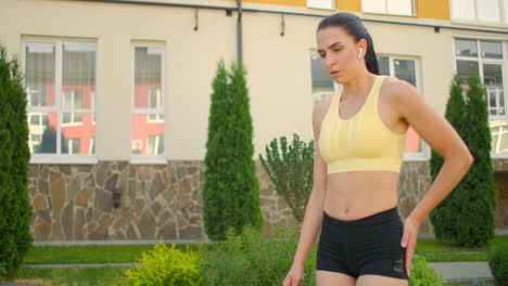 una mujer cansada después del entrenamiento respira y descansa en un parque de la ciudad. mujer joven determinada respira fuertemente se prepara para el ejercicio físico