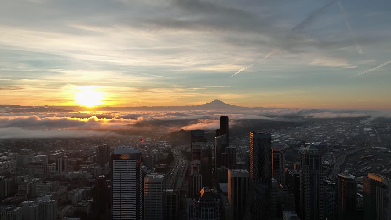 O nascer do sol ilumina as nuvens sobre Seattle com o Monte Rainier ao longe.