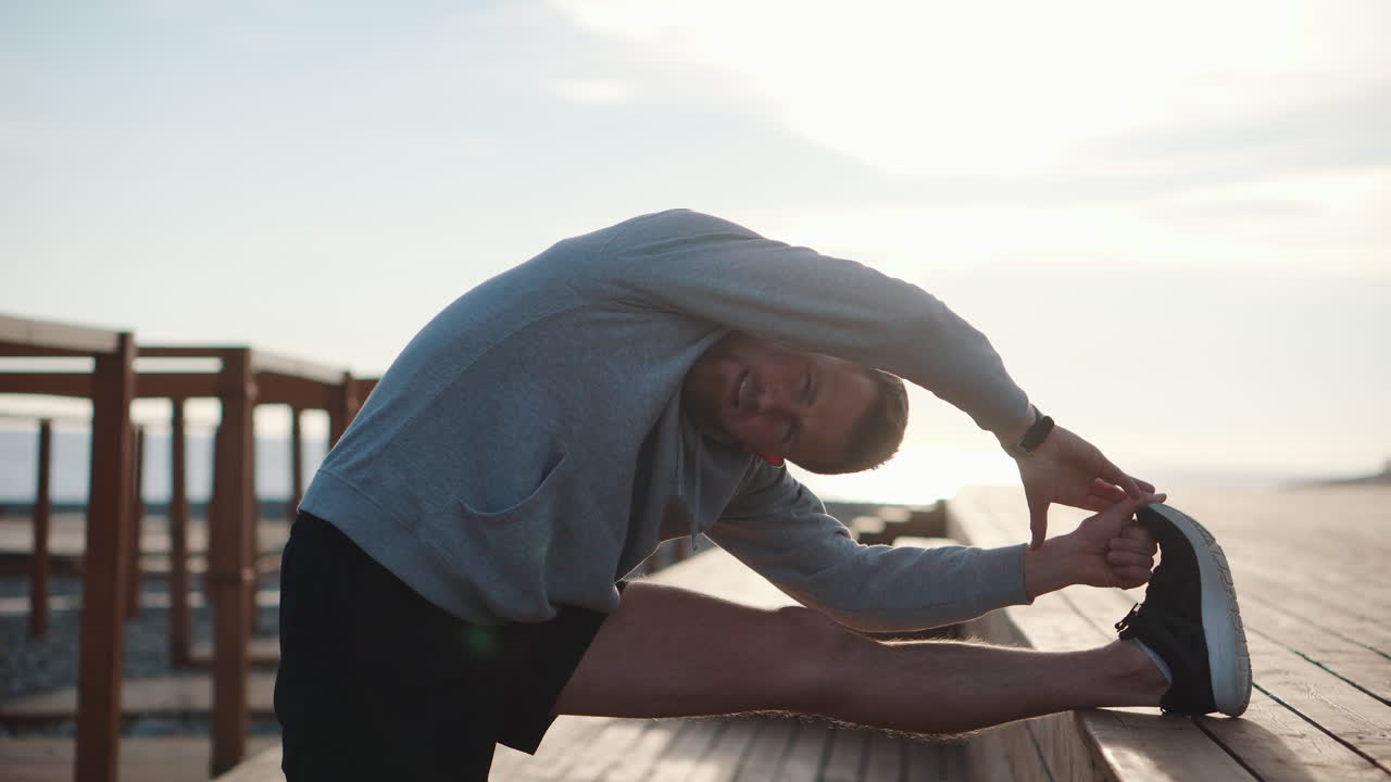 Man Stretching on a Wooden Deck at the Beach