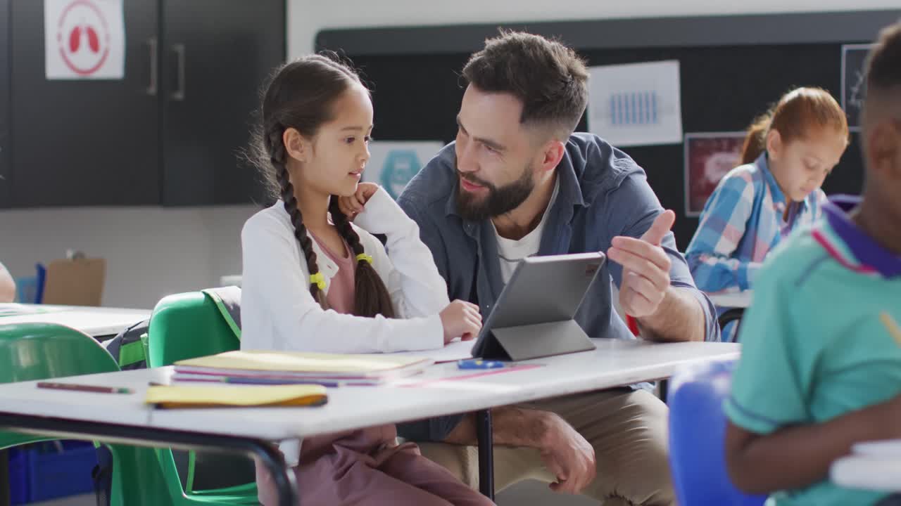 maestro masculino diverso y escolares felices usando tableta en el aula de la escuela