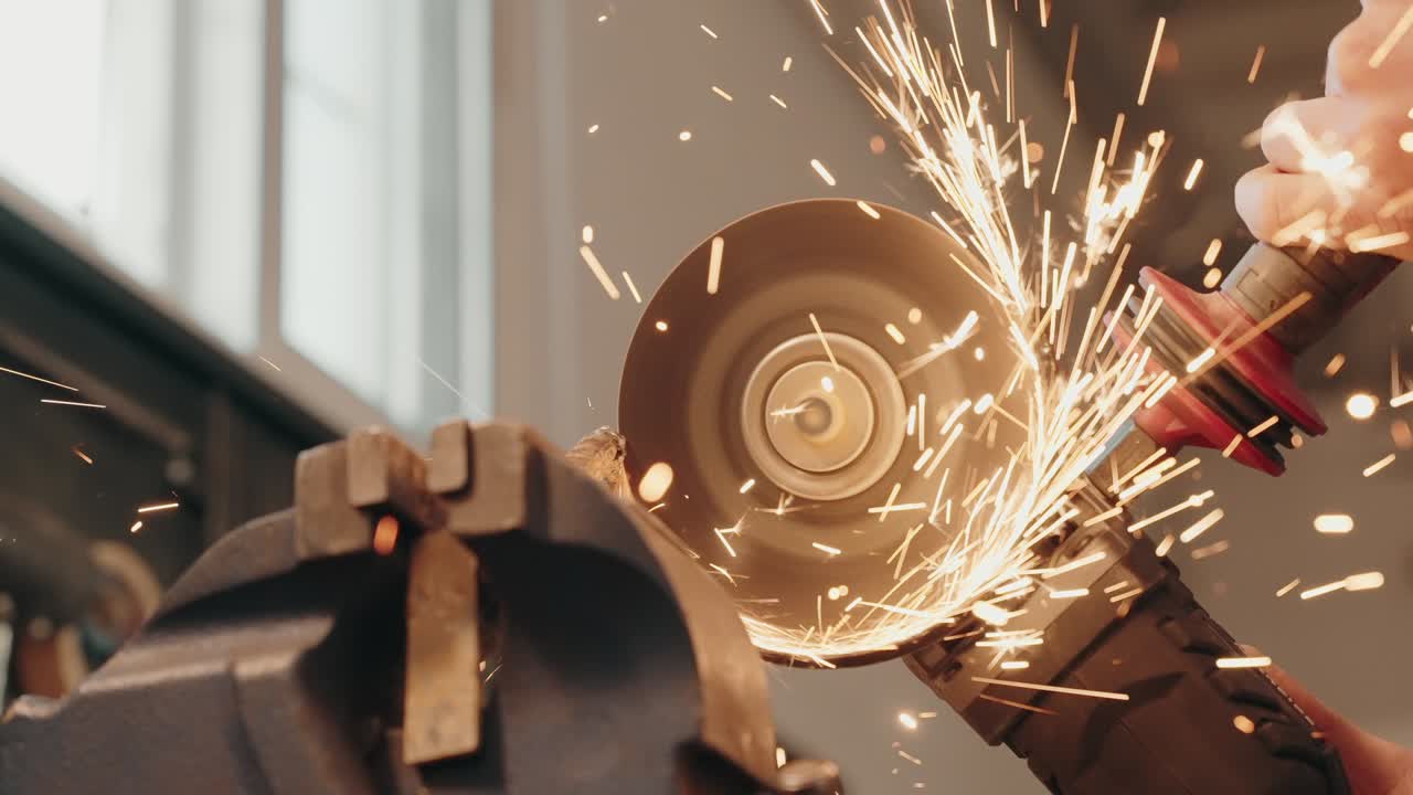 Worker using angle grinder to cut metal with sparks flying indoors - slow motion