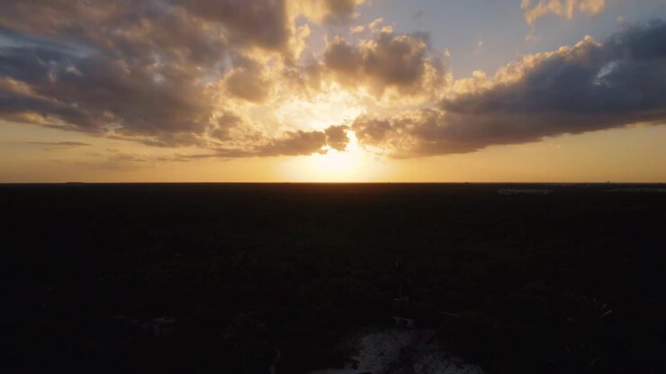 Vista aerea di un drammatico cielo al tramonto con una rivelazione cinematografica della spiaggia sul Mar dei Caraibi a Gitano Tulum.