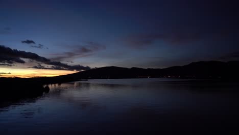 calm ocean view sunset with silhouette of mountains in the background with dark blue skies