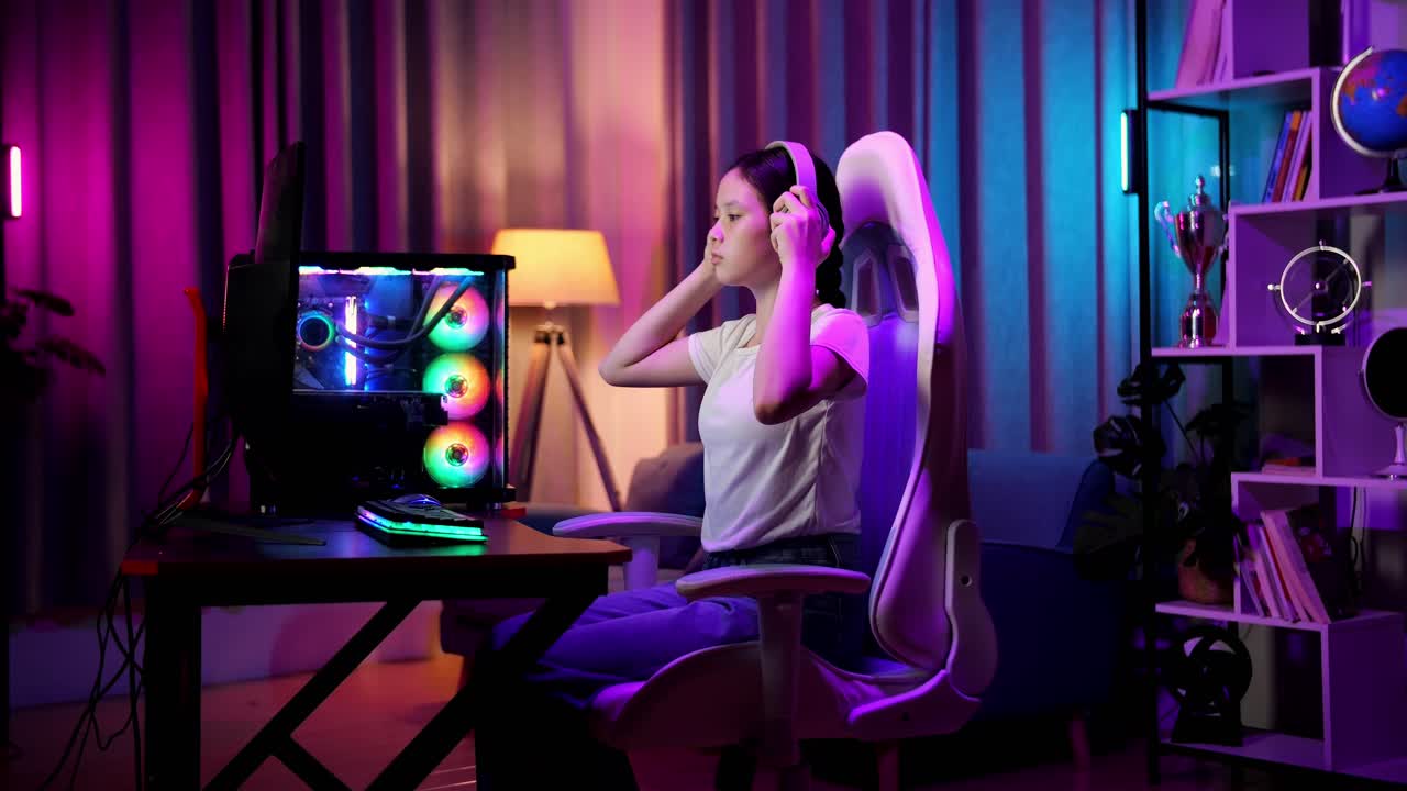 una adolescente asiática que usa auriculares y comienza a jugar videojuegos en la computadora