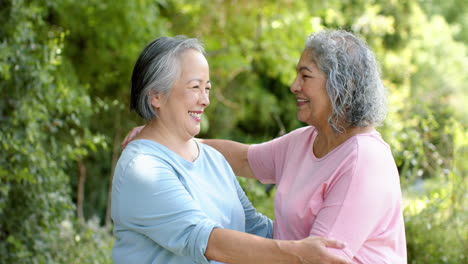 senior biracial woman and asian woman embrace outdoors