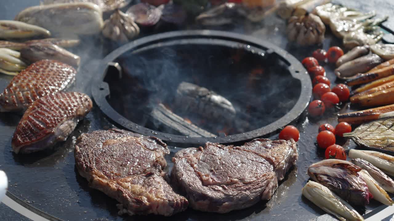 Steaks and vegetables sizzling as tongs flip them on a fire pit
