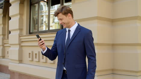 Retrato-De-Un-Hombre-De-Negocios-Alegre-Usando-Un-Teléfono-Móvil-Al-Aire-Libre.-Empresario-Emocionado