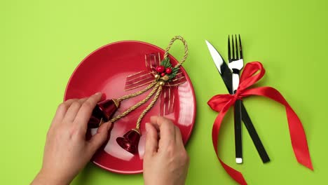 red round plate, knife with fork and christmas decor on a green background